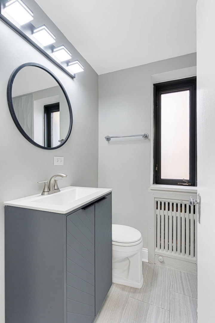 Bathroom with gray vanity and round black mirror